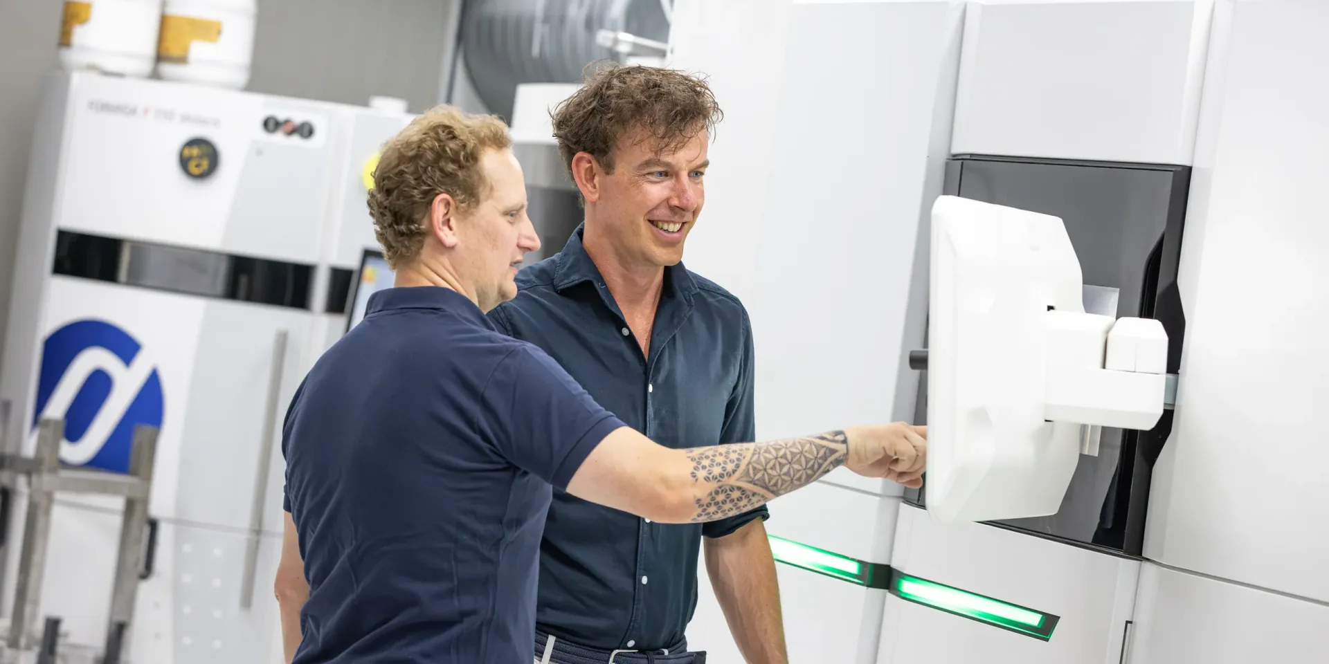 Twee Parts on Demand engineers bespreken een wit PA12 SLS-onderdeel bij een SLS-printer